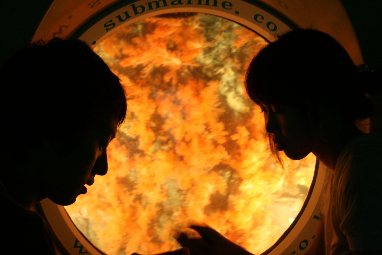 Two silhouettes against a glowing submarine porthole